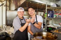 Chef Rookie Kim (Left) and Chef Michael Lee pose making bull horns in the shared kitchen of M Kokko and M Sushi