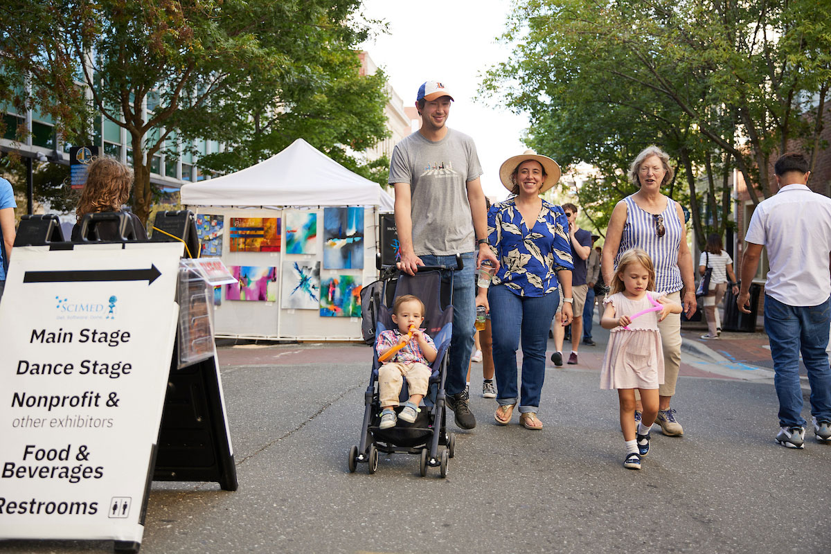 A family of five walks along the street past art vendors during Centerfest Arts Festival